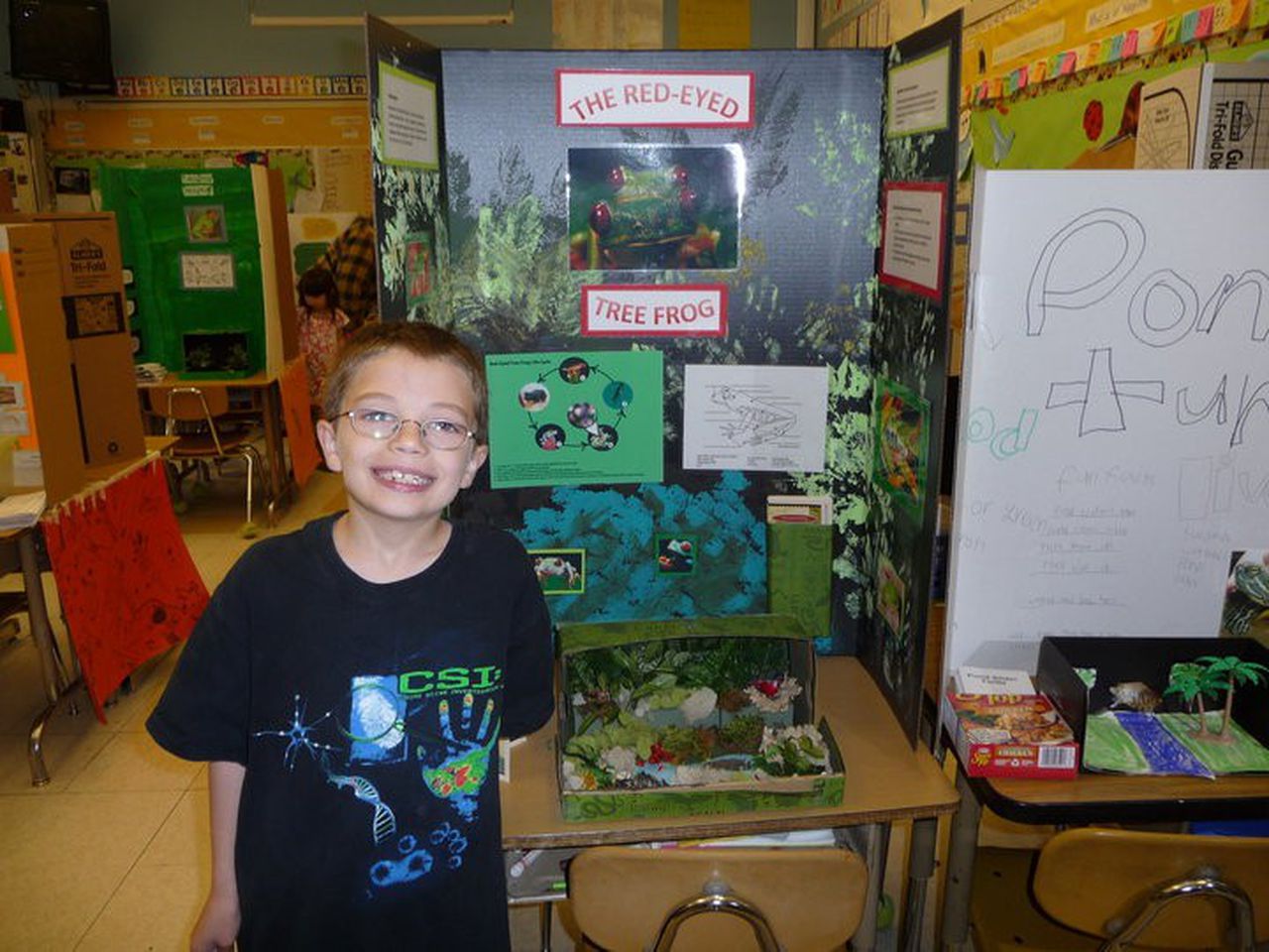 wide grinning boy of 7. he wears glasses and a CSI T shirt.