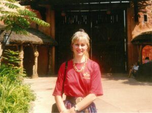 blonde haired lady standing in the sun smiling into the camera