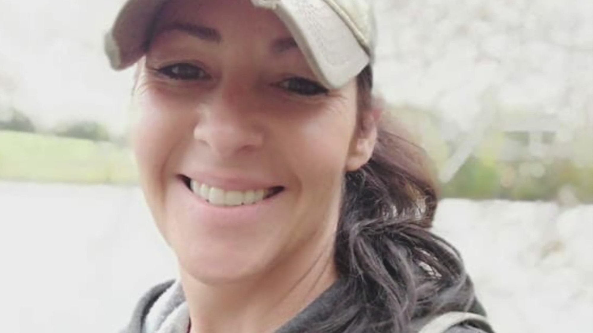 pretty dark haired lady with baseball cap smiling into camera