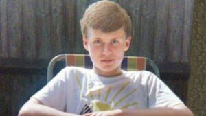 a young lad,15, with light brown hair sits and looks into the camera. 