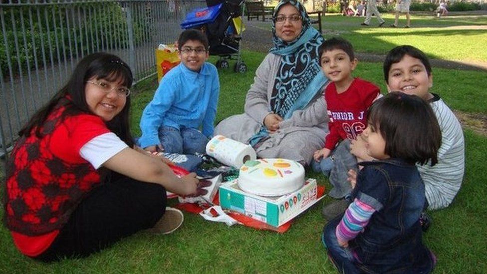 a mother and five children at apicnic smile into the camera